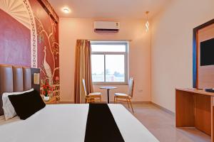 a bedroom with a bed and a table and a window at Hotel O Gomti Garden And Resort in Jhānsi