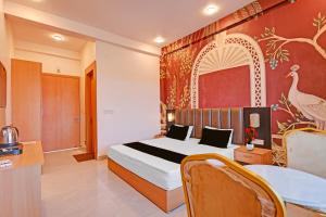 a hotel room with a bed and a table and chairs at Hotel O Gomti Garden And Resort in Jhānsi