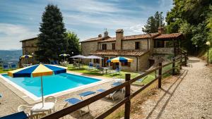 a pool with chairs and umbrellas in front of a house at Agriturismo Monte Acuto in Umbertide +57 photos