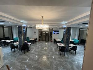 a lobby with tables and chairs and a chandelier at HIQ Hotel Home Inn Qusar in Qusar