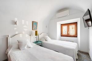 a white room with two beds and a tv at Molino Son Moll in Cala Ratjada +31 photos