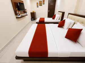 two beds in a room with red and white at Parth Paradise Hotel in Indore +11 photos