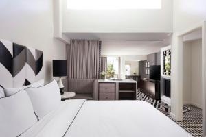 a bedroom with a white bed and a living room at Chamberlain West Hollywood in Los Angeles