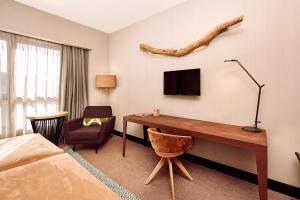 a hotel room with a desk with a tv and a bed at Barceló León Conde Luna in León