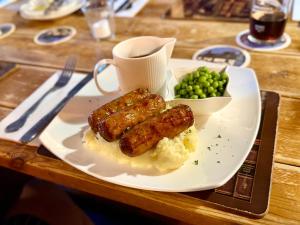 a plate of food with sausages and mashed potatoes and peas at Cross Keys Hotel Chatteris in Chatteris