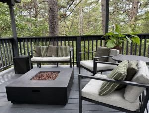 a porch with two chairs and a table and a fire pit at Loblolly Pines Adventure Aframe #2 in Eureka Springs