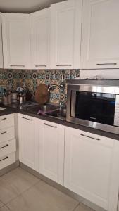 a kitchen with white cabinets and a microwave at guesthouseminturnoit Lucia Sparagna in Minturno