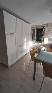 a kitchen with white cabinets and a table and chairs at guesthouseminturnoit Lucia Sparagna in Minturno