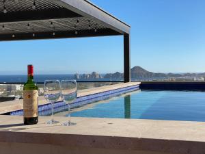 two wine glasses sitting on a ledge next to a swimming pool at Sunset view Penthouse 302 in Cabo San Lucas