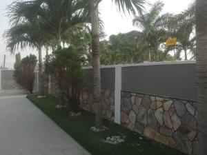 a retaining wall with palm trees and a fence at FREDJACKSAIR BnB in Koforidua +10 photos
