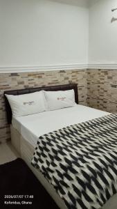 a bed with black and white sheets and pillows at FREDJACKSAIR BnB in Koforidua