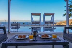 a table with two plates of food and orange juice at Blue Vedere in Agia Pelagia