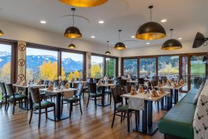 a dining room with tables and chairs and large windows at Panoramahotel Kühbergalp in Gunzesried