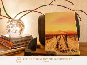 a table with a painting and a vase and books at La Terrasse du Tonnelier - 92m2 - plein centre médiéval - sauna - terrasse 20m2 - garage in Kaysersberg