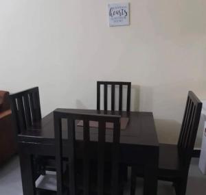 a black dining room table and chairs with a sign on the wall at Migzhome in Dodoma