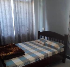 a bedroom with a bed with a blue and white blanket at Migzhome in Dodoma