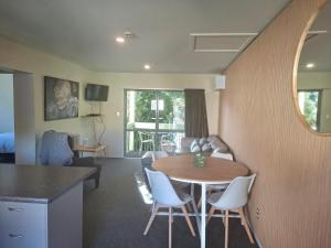 a living room with a table and chairs and a kitchen at La Rochelle Motel in Akaroa