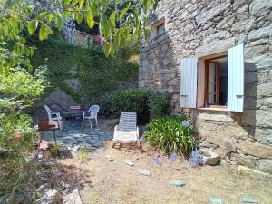 a patio with chairs and a table and a building at Casetta - Appartement dans maisonnette rustique in Cognocoli-Monticchi
