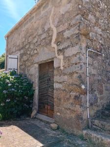 a stone building with a door in the side of it at Casetta - Appartement dans maisonnette rustique in Cognocoli-Monticchi +3 photos