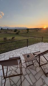 a patio with two chairs and a table and the sunset at V Chalet in Žabljak +6 photos