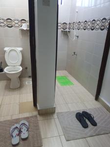 a bathroom with a toilet and a pair of slippers at stayscape homes nanyuki in Nanyuki
