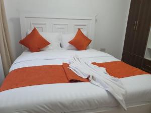 a bed with orange and white pillows on it at stayscape homes nanyuki in Nanyuki