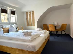 a bedroom with a large white bed and a table at Hotel Hasen Kaufbeuren Allgäu in Kaufbeuren