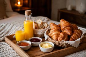 a tray of croissants and other breakfast foods on a bed at Love Room -La Suite Secrète in Rodez