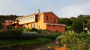 a large orange building in a yard with a garden at El Mirador de Deva in Deva