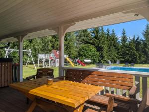 a wooden picnic table on a deck with a pool at Chill House Sedranki in Olecko