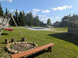 a wooden bench in a park with a playground at Chill House Sedranki in Olecko +12 photos