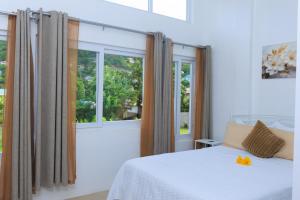a bedroom with a bed and two windows at Agape Suites-Room 3- 1st Floor in Soufrière