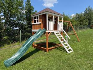 a playground with a slide and a play house at Domki Mucharskie in Mucharz