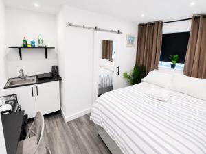 a white bedroom with a bed and a sink at UNLIMITED-PEACE PRIVATE STUDIO APARTMENTs in Weston-super-Mare