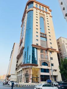 a tall building with cars parked in front of it at فندق رفاهية العزيزية in Al ‘Azīzīyah