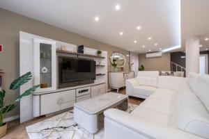 a living room with white furniture and a flat screen tv at Villa Machim - Heated Pool - View in Machico