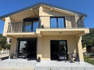 a house with a balcony and tables and chairs at FOREST apartments in Bijela