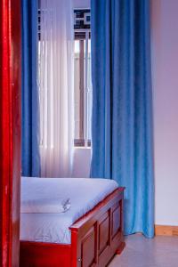 a bed in a room with blue curtains and a window at Gugga Suites Mbale in Mbale