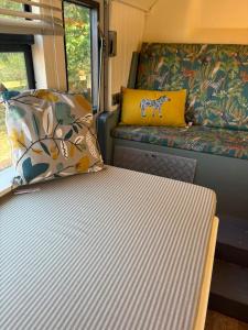 a bed in an rv with a couch and pillows at Debdale Bus Retreat in Little Dalby