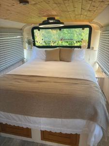 a bed in the back of an rv with a window at Debdale Bus Retreat in Little Dalby +8 photos