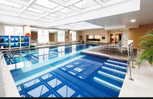 a large pool with blue water in a building at Flat em Alphaville Hotel Comfort in Barueri