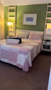 a bedroom with a bed and a green wall at Flat em Alphaville Hotel Comfort in Barueri