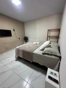 a bedroom with a bed and a tv on the wall at Maruva Chalé in Aquiraz