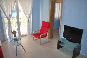 a living room with a red chair and a tv at Villa Lunaris in Maslinica