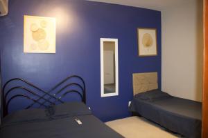 a bedroom with two beds and a blue wall at APT térreo completo - 2 Quartos - 2 Ar-condicionados, Cozinha, Garagem, WI-FI- Maurício Nassau, Perto de tudo in Caruaru