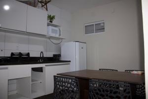a kitchen with a table and a refrigerator at APT térreo completo - 2 Quartos - 2 Ar-condicionados, Cozinha, Garagem, WI-FI- Maurício Nassau, Perto de tudo in Caruaru