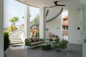 a living room with green furniture and a staircase at New Capri Condo in Bang Tao by Lofty in Ban Thalat Choeng Thale