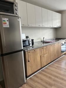 a kitchen with a stainless steel refrigerator and wooden cabinets at Marina del Sol Executive Apartment in Talcahuano