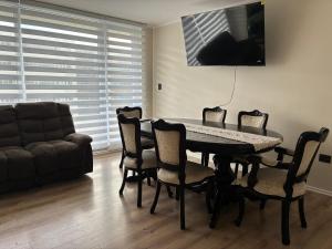 a dining room with a table and chairs and a couch at Marina del Sol Executive Apartment in Talcahuano +2 photos