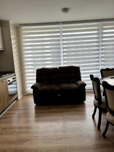 a couch in a living room with a window with blinds at Marina del Sol Executive Apartment in Talcahuano